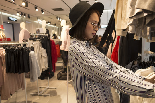 帽子を被った女性は服屋で買い物をしている。