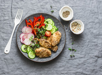 Sesame breading teriyaki baked chicken breast and fresh vegetables. Baked chicken and tomatoes, cucumbers, peppers, radishes, micro greens salad, top view. Flat lay