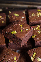 Homemade chocolate brownies with pistachios on dark background. Copy space, top view
