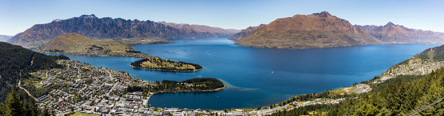 Fototapeta na wymiar A panoramic landscape of Queenstown, New Zealand with Lake Wakatipu under a blue sky