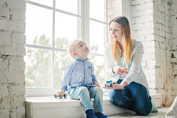 Beautiful Mother and Little Son Playing with Toys at Home