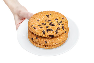 Woman hand holds plate with chocolate chip cookies. Isolated on white.