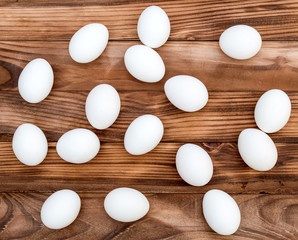 White eggs on the brown wooden table. Top view.