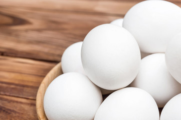 Wooden plate with heap of eggs on the table. close up.