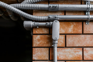 steel pipe electricity system work on brown brick wall background interior work detail