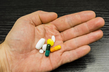 A set of different pills and pills on a sick hand.