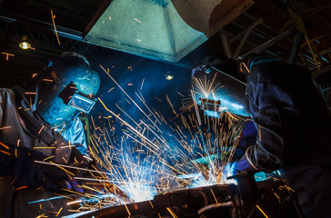 Teamworker with protective mask welding metal