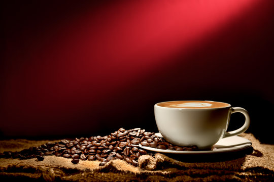 Cup of coffee latte and coffee beans on reddish brown background
