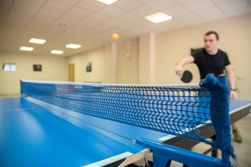 A man playing table tennis on a blue table in the room