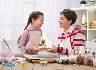 Mother and girl baking cookies, home kitchen interior, homemade food concept
