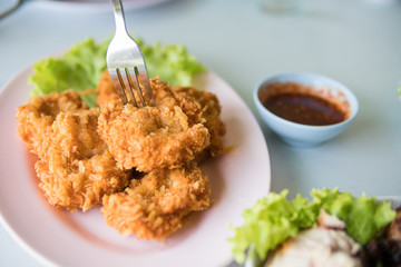 Thai fried shrimp cake on pink plate with sweet chili sauce.