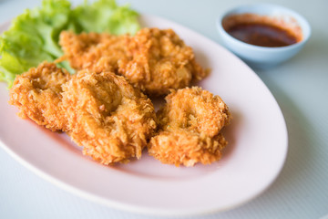 Thai fried shrimp cake on pink plate with sweet chili sauce.