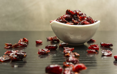 Dried cranberries in a bowl and scattered on the table.