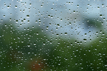 Rain droplets on a window with green background