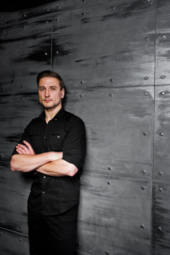 Studio portrait of stylish man wear on black shirt against steel wall.