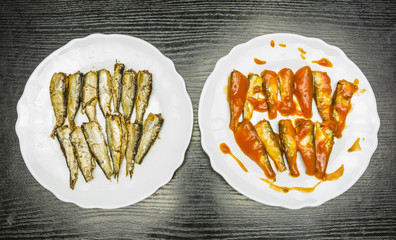 Plates with smoked sprats with oil and tomato sauce. View from above.