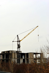 Fototapeta na wymiar Mounting crane at construction of apartment building, cloudy autumn day