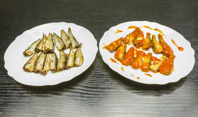 Plates with smoked sprats in oil and tomato sauce.