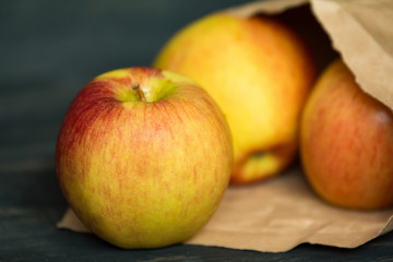 fresh ripe apples in a paper package on a black wooden background