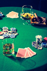 Closeup of green table for poker with whiskey and cards