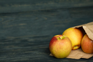 fresh ripe apples in a paper package on a black wooden background