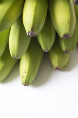 Layers of green and yellow baby bananas on white, copy space, vertical aspect