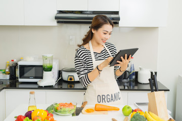 Young asian woman using a tablet computer to cook in her kitchen.