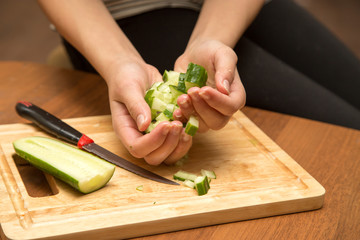 Slicing cucumber with a knife on the board