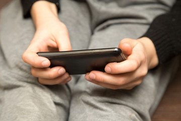 The boy plays the game on the phone