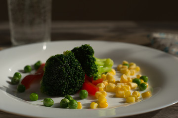 Broccoli with vegetables on a white plate. Vegetarianism. Healthy food.