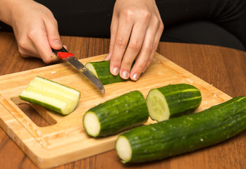 Slicing cucumber with a knife on the board