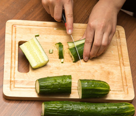 Slicing cucumber with a knife on the board