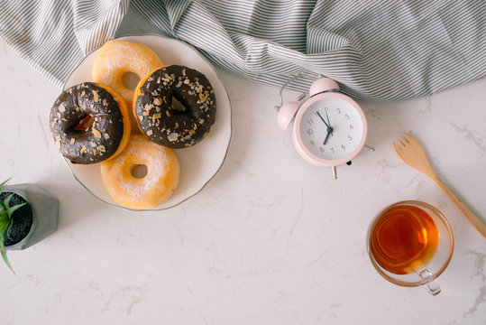 Overhead view of chocolate cake donuts with salted caramel glaze with a cup of espresso on marble table top. Afternoon me time book reading with dessert and coffee. Text space images