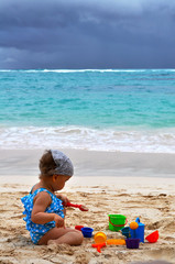 little girl is playing in the sand before the approaching storm