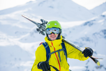Portrait of sportive man in helmet with skis on his shoulder