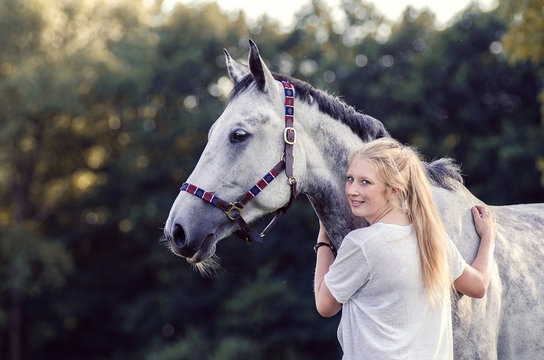 lachende Frau umarmt Pferd