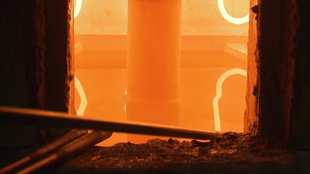 A steady shot of a burning hot oven for glass in a factory.
