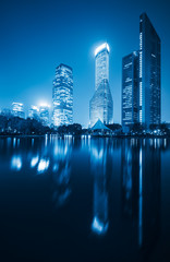 blue toned of modern skyscrapers standing by park lake at night,shanghai,china.