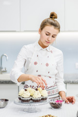 young woman cook decorates cupcakes
