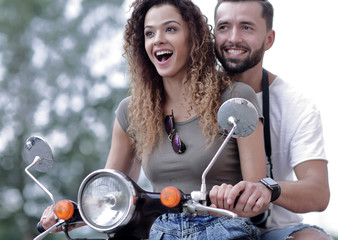 Attractive couple riding a scooter on a sunny day in the city