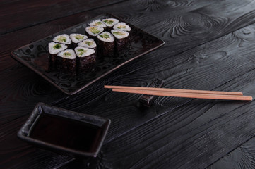 Flower from rolls maki sushi on a black stone plate. Fresh made Sushi set with cheese and cucumber. Traditional Japanese cuisine.