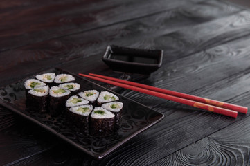 Flower from rolls maki sushi on a black stone plate. Fresh made Sushi set with cheese and cucumber. Traditional Japanese cuisine.