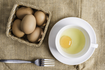 Fresh egg in white cup on cloth background.