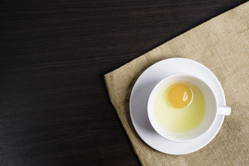 Fresh egg in white cup on cloth background.