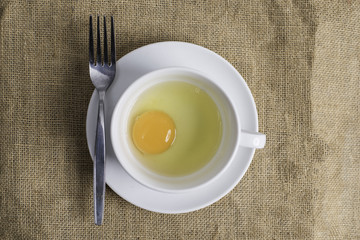 Fresh egg in white cup on cloth background.