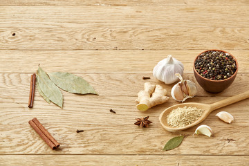 Composition of powder spices on spoon and different sorts of spicies on wooden table background, selective focus