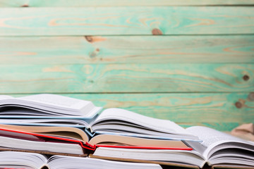 Stack of open books pile of various books on wooden background. With copy space for your text