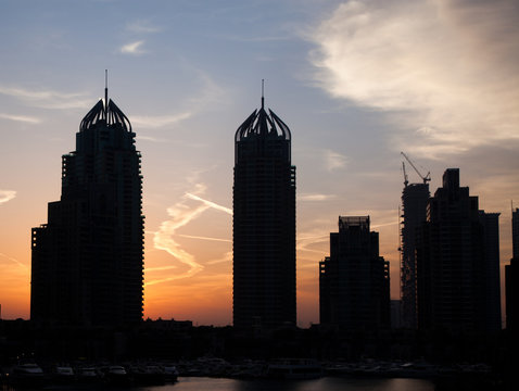 DUBAI, UAE - FEBRUARY 2018: Silhouettes of modern skyscrapers shining in sunrise lights  in Dubai Marina in Dubai, UAE.