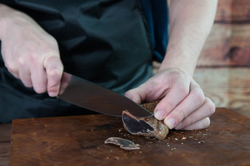 Portion of Beef Jerky cutting into slice on a cutting table with dark beer glass and a kitchen knife on vintage wooden background, man standing behind