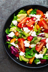 Vegetable dish, salad with avocado, pepper, tomato, italian mix, fresh lettuce, feta cheese and pine nuts. Healthy food. Top view